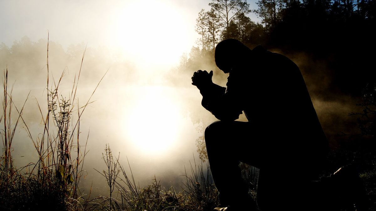 man praying in a nature setting